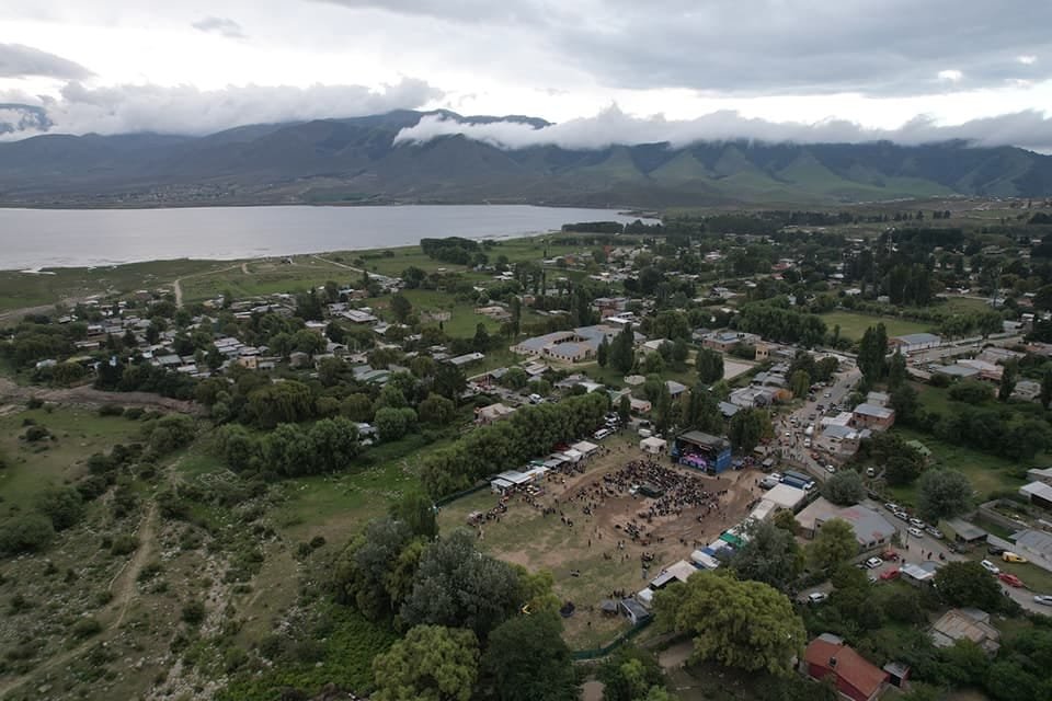 Vista aérea de la villa entre el dique y los cerros, con un escenario montado en un predio