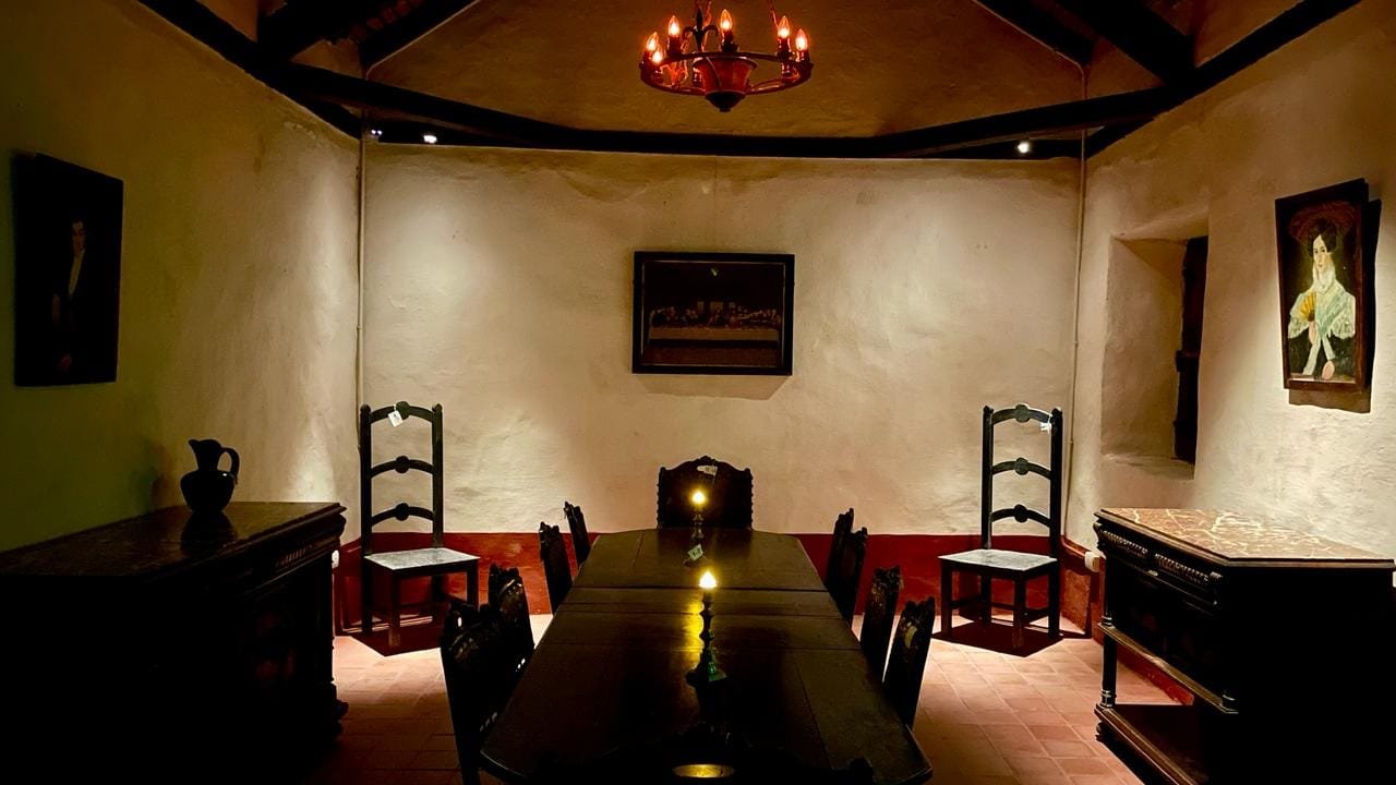 El comedor de época, con la mesa larga, las sillas de madera y los retratos en las paredes